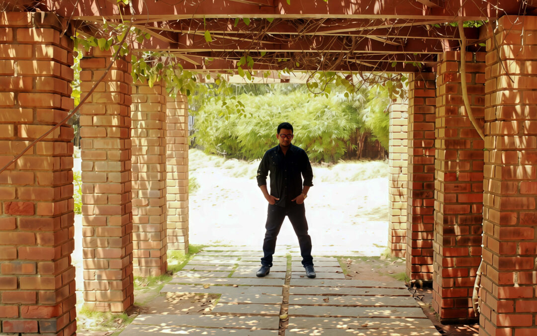 Portrait of a man posing under a beautiful brick pergola surrounded by lush greenery at Semmozhi Poonga, a popular photoshoot location in Chennai.